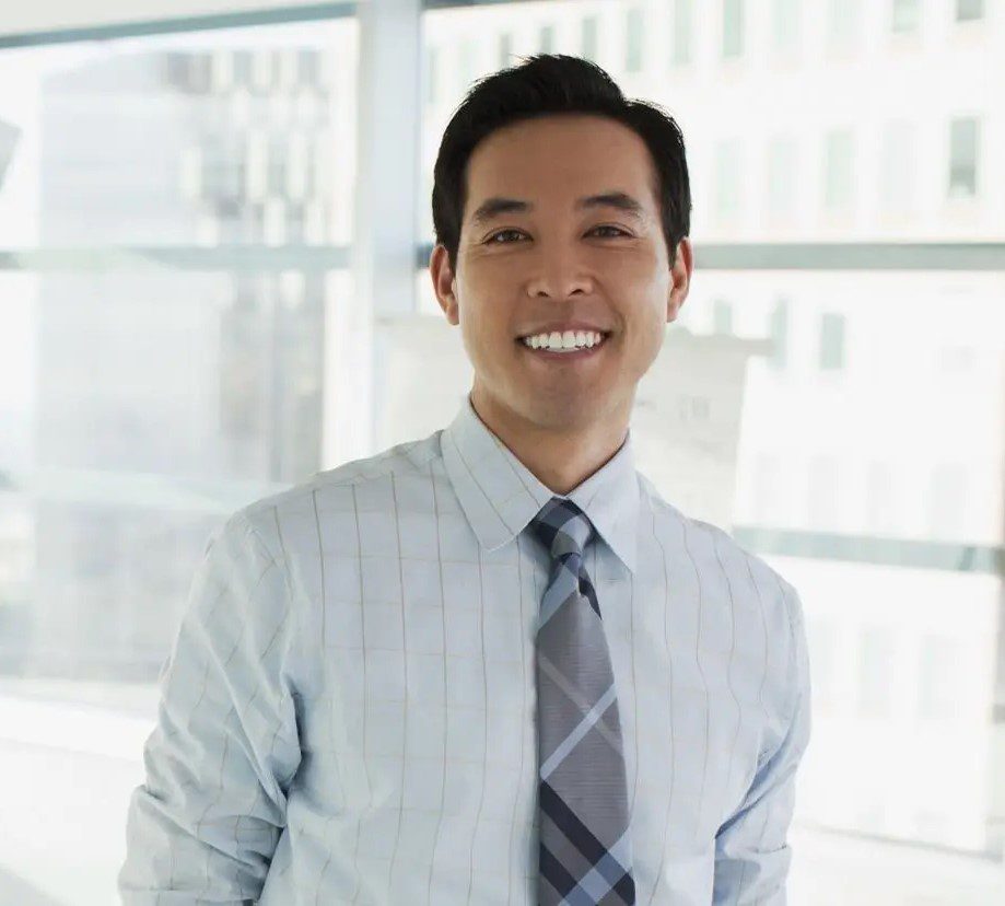 A man in a dress shirt and tie smiling.